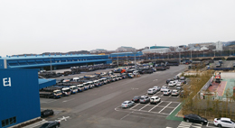삼일 신물류터미널의 모습이다. 물류센터 앞의 넓은 주차장에는 여러 대의 화물운송차량와 승용차가 주차되어있다.